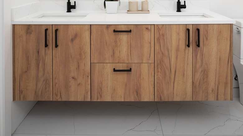 A floating white oak vanity cabinets in a bathroom with ceramic tile flooring.