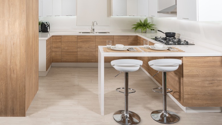 A modern kitchen with white oak cabinets and white washed floors, as well as a dining peninsula.
