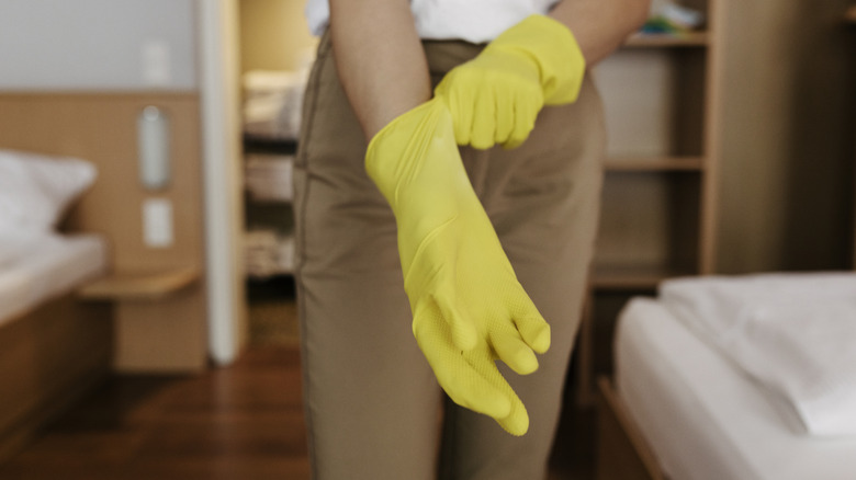 A woman removing a pair of yellow rubber gloves