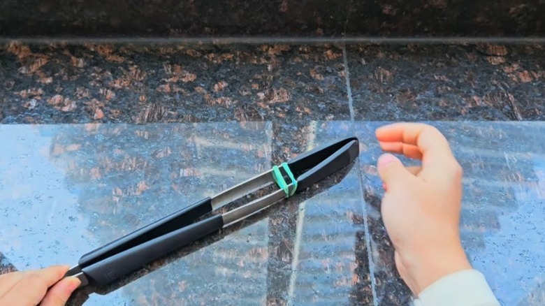 tongs closed with a blue band on a countertop