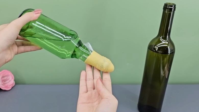 rubber glove tip covering the opening of a green glass bottle