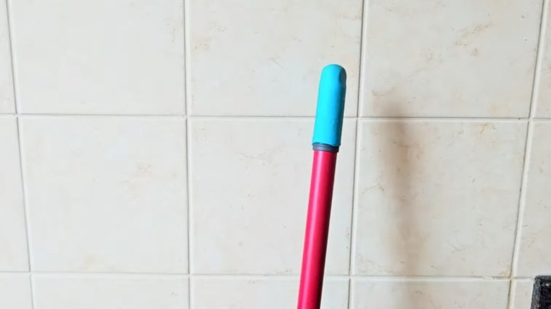 Tip of a broom handle covered in rubber glove
