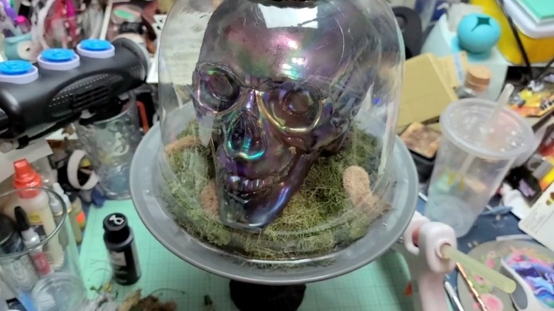 Holographic skull on moss in a glass cloche