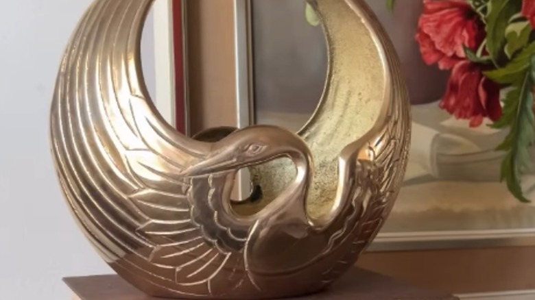 A polished brass bird basket sitting on a shelf