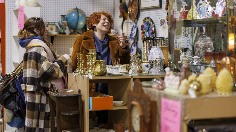 A pair of happy women shop at a thrift store.
