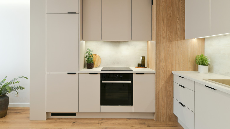 Built-in stove in minimalist kitchen, installed flush with cream cabinets