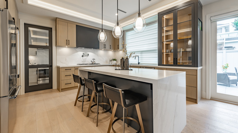 luxury kitchen with waterfall island, glass cabinets, and butler's pantry