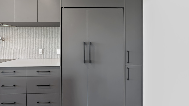 Kitchen with gray cabinetry and built-in refrigerator with custom matching doors.