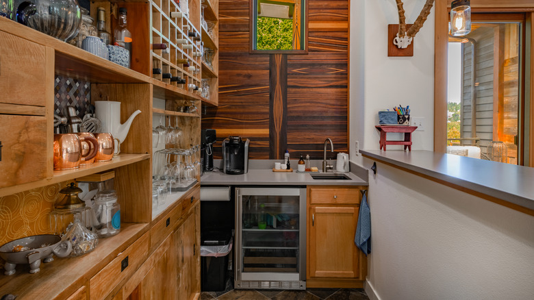 Butler's pantry with wood cabinetry, sink, and mini fridge