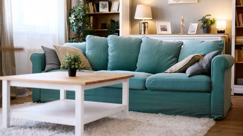 A blue green sofa sits in a living room with gray walls and a coffee table