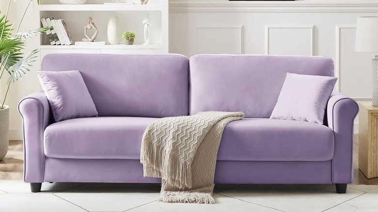 A lilac sofa with a beige throw in an airy living room