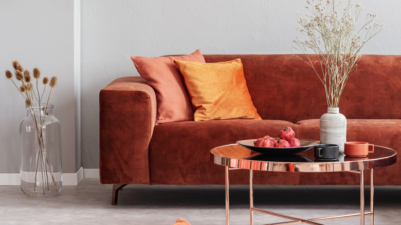 A sofa in rusty red and a shiny gold coffee table