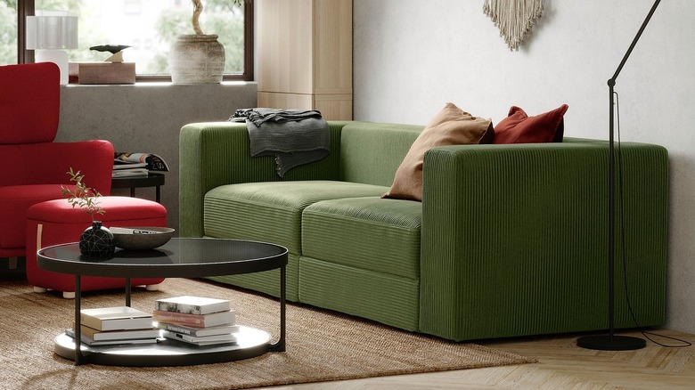 A dark green sofa in a comfy livnig room with cushions and a coffee table