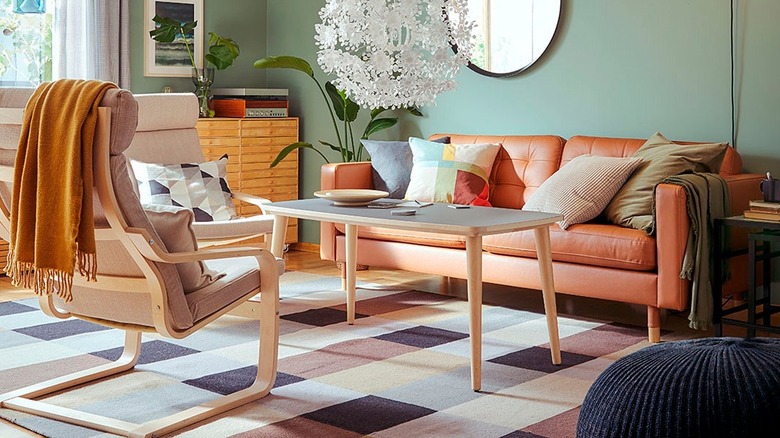Orange leather sofa in a retro home with green wallpaper and wooden chairs