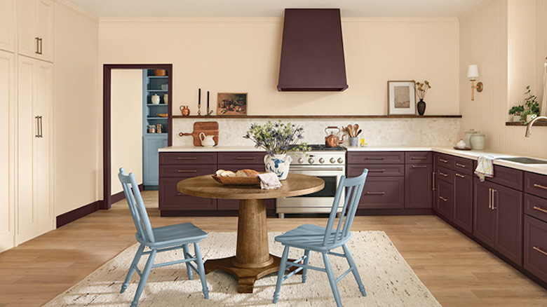A large kitchen with cream walls and aubergine cabinets.