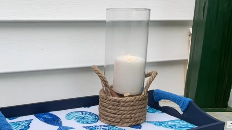 Outdoor candle holder with rope wrapped around it displayed on a tray