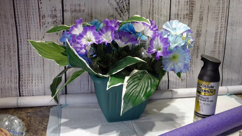 Planter filled with silk flowers next to can of spray primer and pool noodle