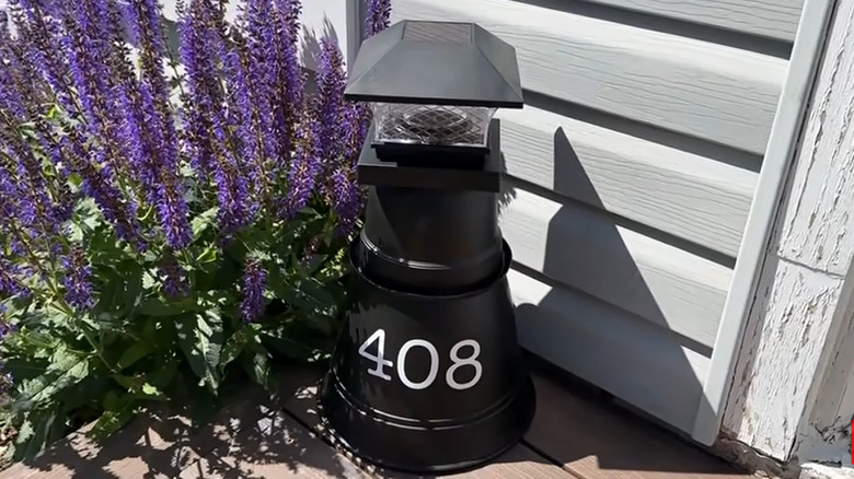House number display made out of flower pots with a solar light on top