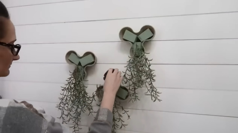 Person placing faux succulents into vertical flower pot display