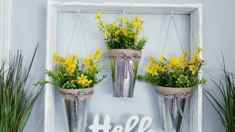 Set of three hanging buckets with yellow flowers in them
