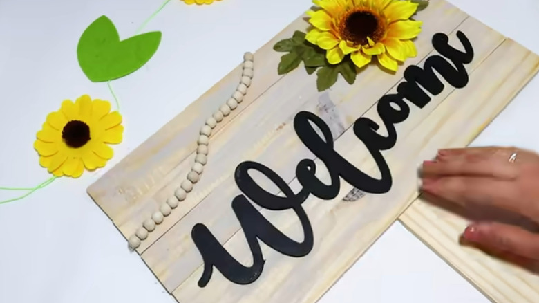 Wood plank welcome sign with wooden bead accents and a sunflower