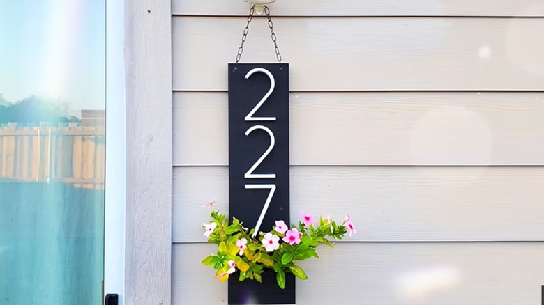 Hanging house number sign with planter filled with flowers