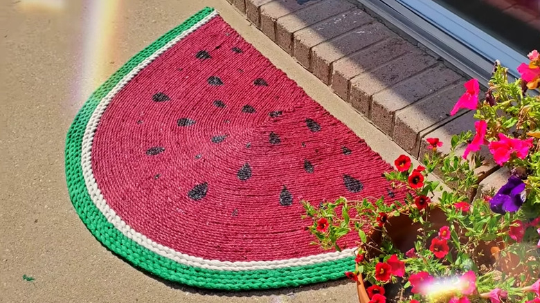 DIY watermelon rug made with Dollar Tree supplies laying by a front door next to a flower pot