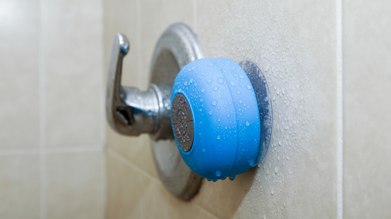 A blue, waterproof shower speaker on the shower wall.
