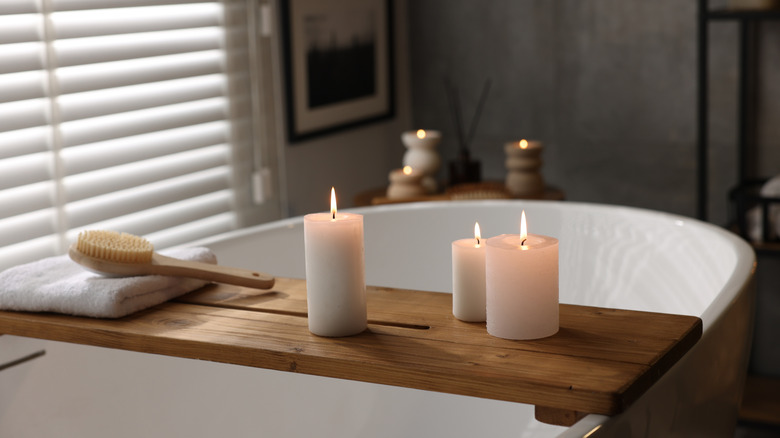 A bath tray across a tub with candles, and candles in the background.