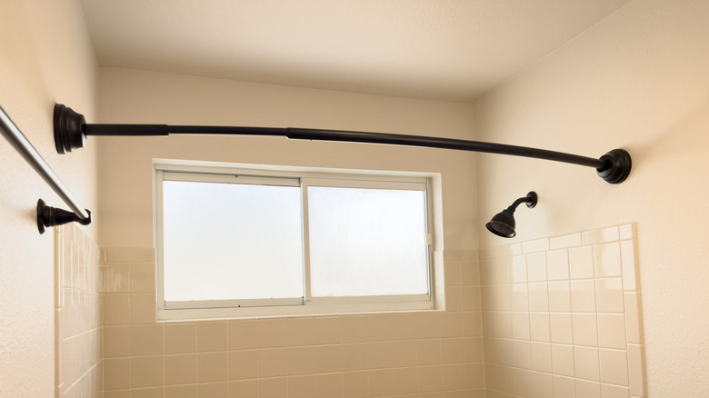 A black curved shower rod over the tub.