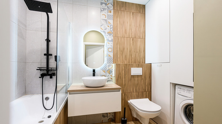 A modern bathroom with a wooden slat accent wall and wallpaper.