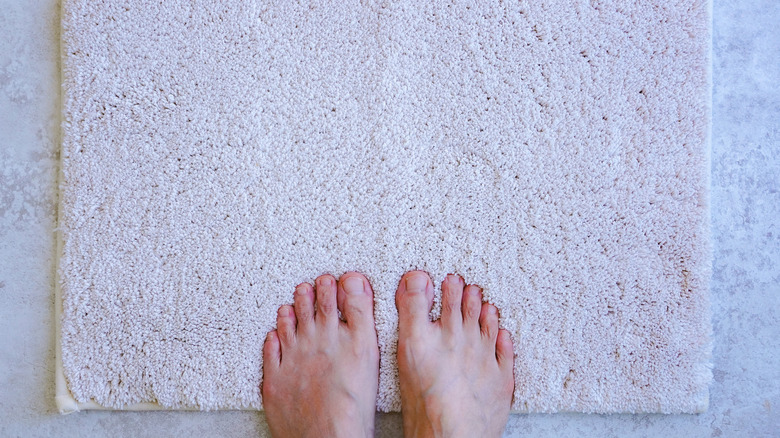 Feet on a fluffy, white bathmat.
