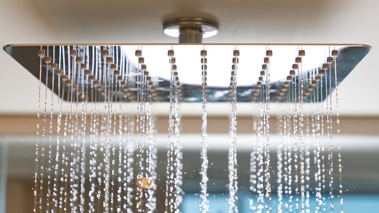 A close up of a rainfall shower head turned on.
