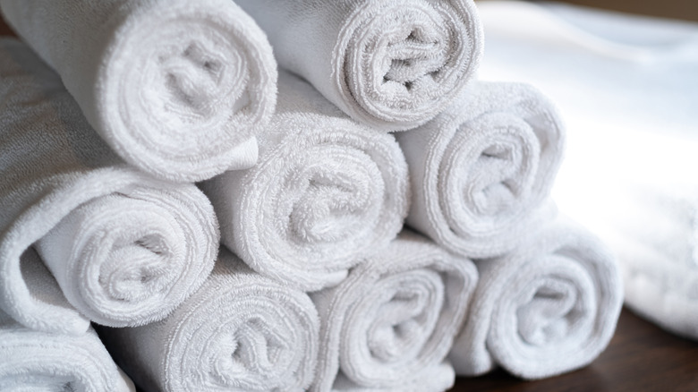 Neatly stacked, rolled white towels on a table.