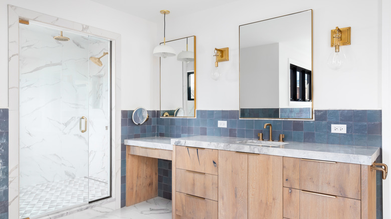 A modern bathroom with matching gold metallic accents and blue tile.