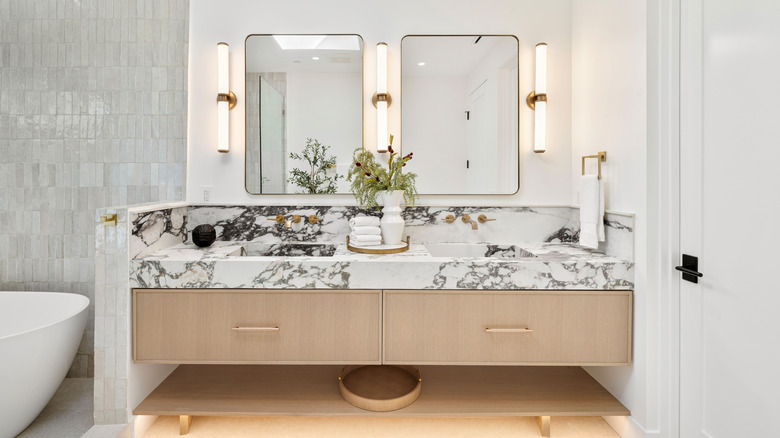 A modern bathroom with a floating, marble vanity, and two rectangular mirrors over a dual sink.