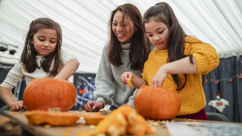 Mother carving pumpkins with kids