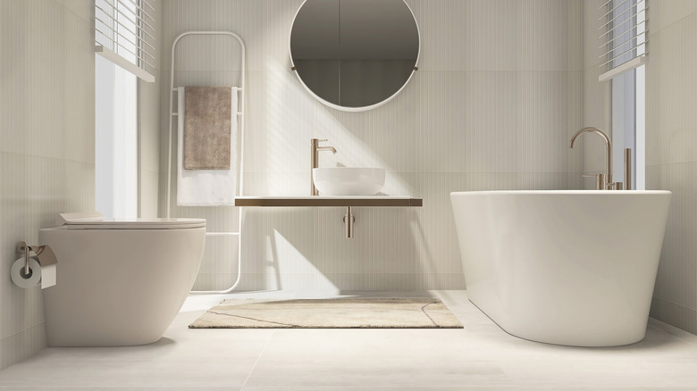 Creamy white bathroom with a towel rack and round mirror
