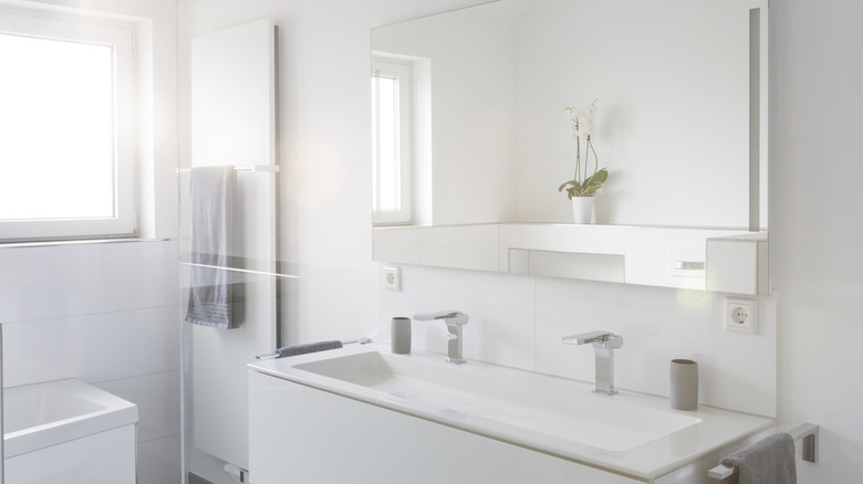 White bathroom with a mirror and bright window