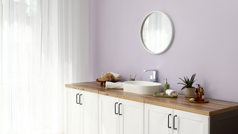 Lilac bathroom with wood countertop and white sink