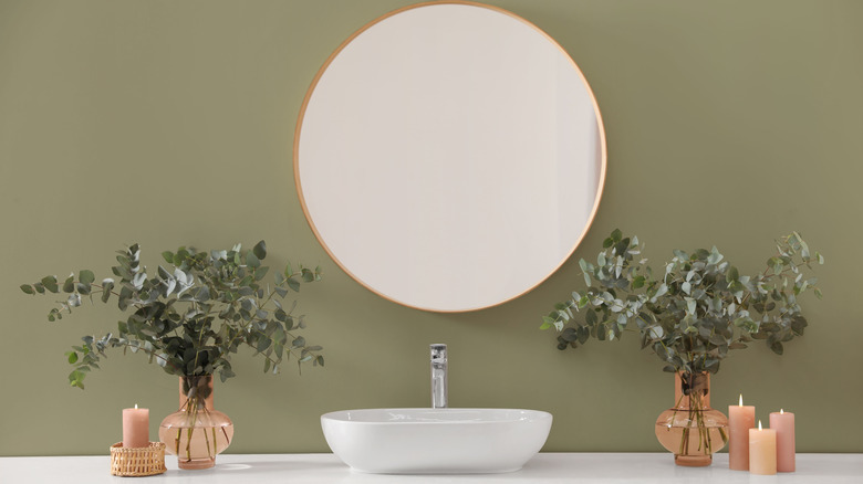 Sage green bathroom with a large round mirror