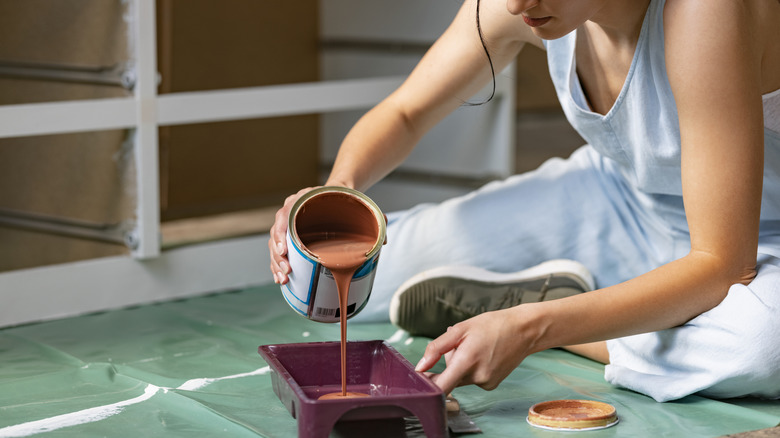 A person pouring floor paint in a container
