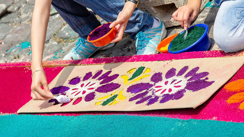 Two people using glitter paste on stencil patterns