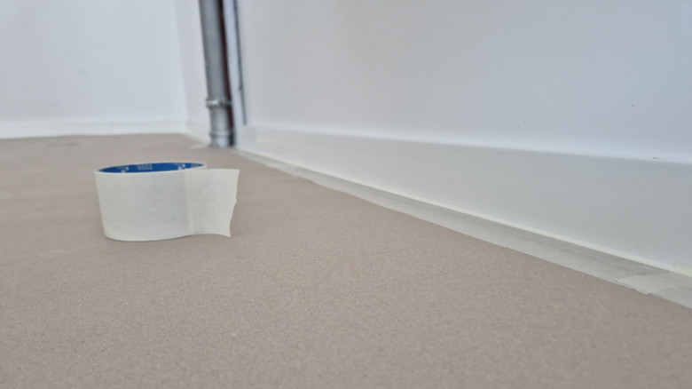 Using masking tape to protect baseboards