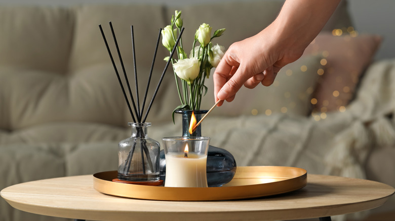 hand lighting candle in living room