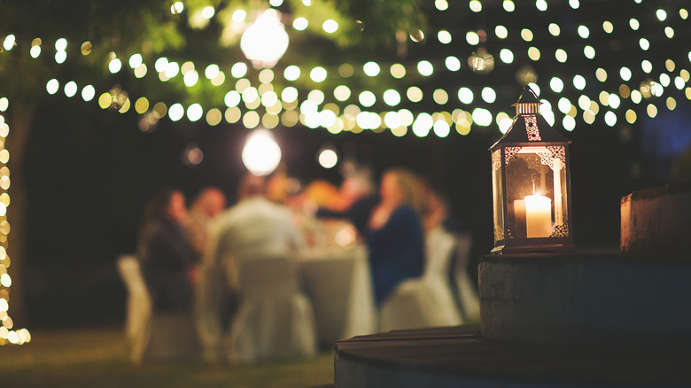 twinkle lights and lantern illuminate backyard party