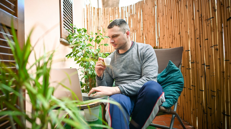 man sitting on reed-fenced patio