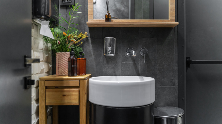 A bathroom with anthracite tiles behind a floating vanity.