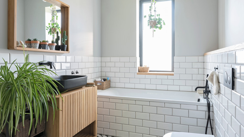 A bathroom with subway tile walls and bath alcove and wooden accents.