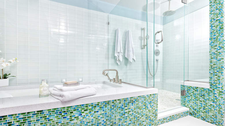 A bathroom with a blue-ish green tiled wall.